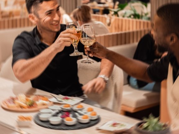 Two men clink glasses at a restaurant