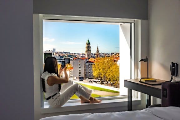 Woman sitting on window sill take a photo of the city