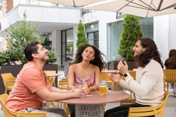 Three friends laugh over drinks