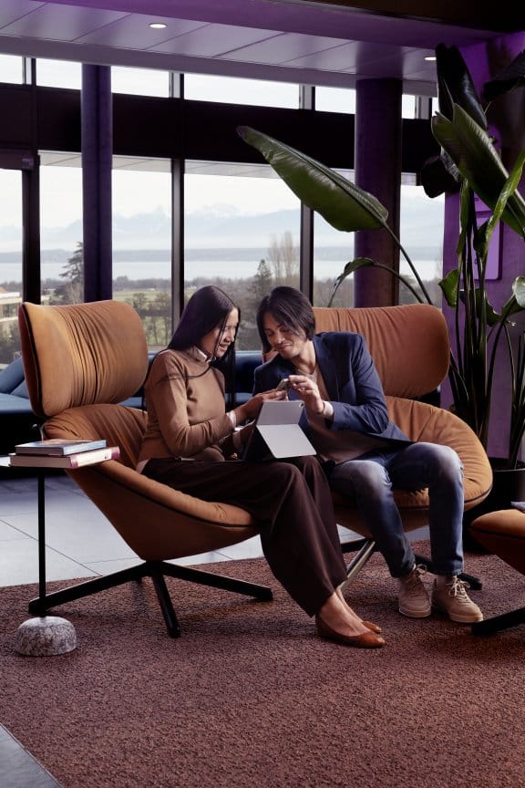 a Couple relax on lounge chairs in an airy hotel lobby