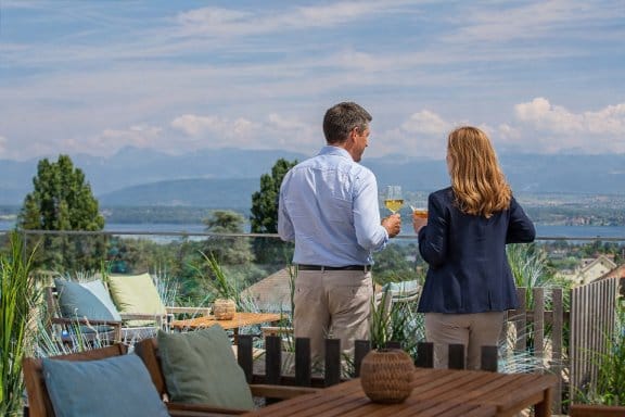 A man and a woman enjoy a rooftop view of the alps