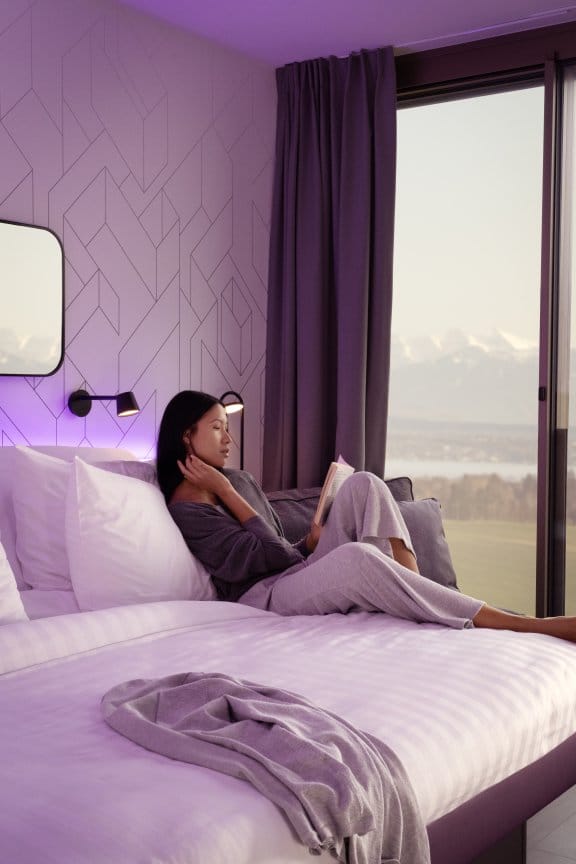 A girl reclined in bed with large windows