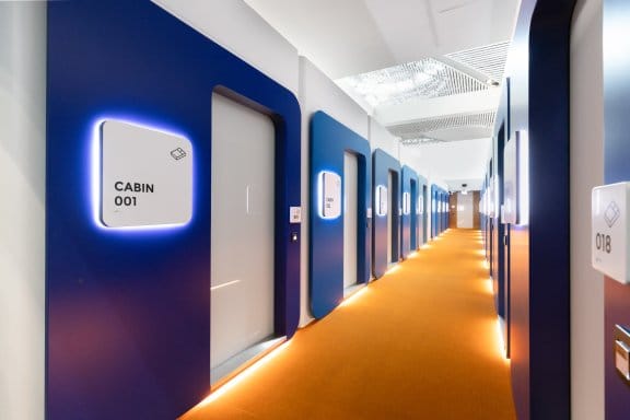 A long modern hotel corridor where each door is signposted by cabin numbers