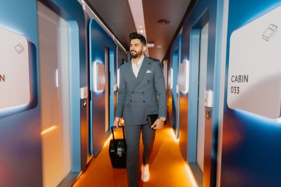 A man wheels his luggage suitcase through a hotel corridor