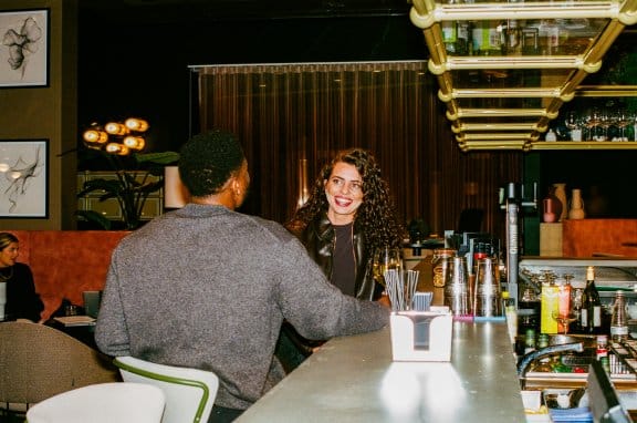 A man and a woman laugh over drinks at a hotel bar