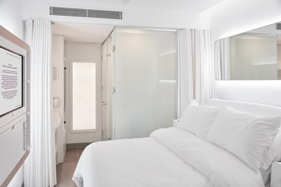 YOTEL Istanbul Airside queen room shows SmartBed opposite large TV next to private bathroom cubicle