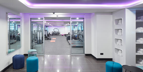 Entrance to YOTEL Istanblu Landside gym shows treadmills behind glass doors with towels for guests