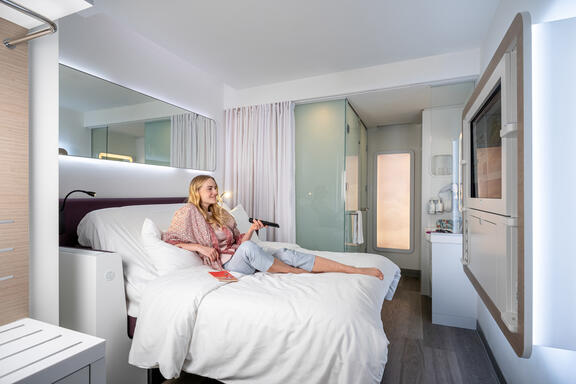 YOTEL Istanbul Airside Premium room with woman lounging and watching TV