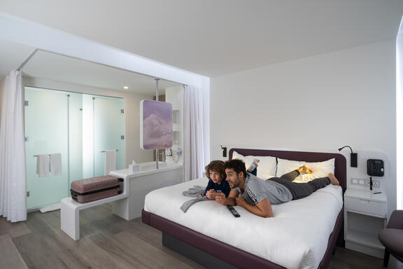 Father and son relax on YOTEL SmartBed inside the First class junior suite