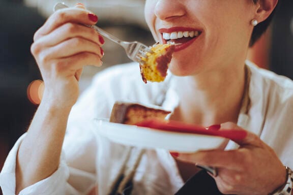 A woman smiles as she eats food
