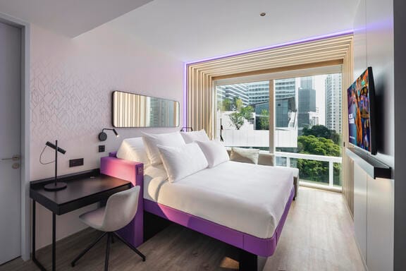 An airy hotel room with floor to ceiling windows