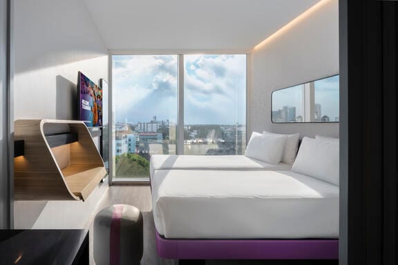 An airy hotel room with floor to ceiling windows
