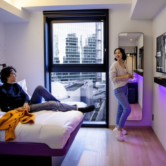 A man and a woman relax in their hotel room with views of Tokyo outside