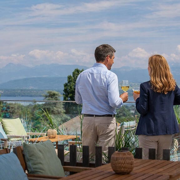 A man and a woman drink on the rooftop of an alpine hotel