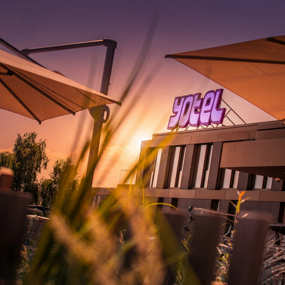 YOTEL property with purple logo and umbrellas during sunset
