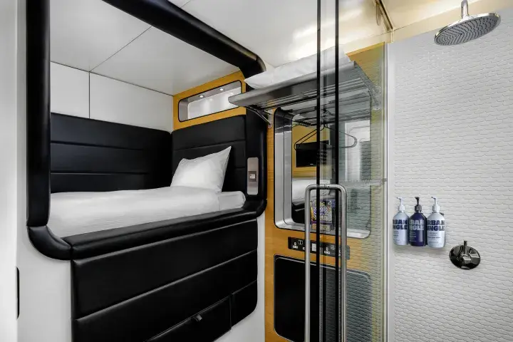 Compact hotel room with smart storage beneath the bed, a shower and a fold-out desk space