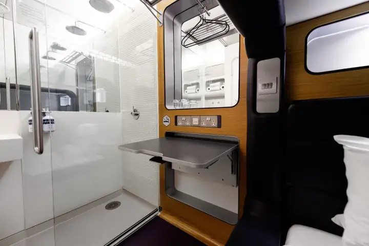 A compact hotel room with a wet room, fold-out desk, smart TV and bed