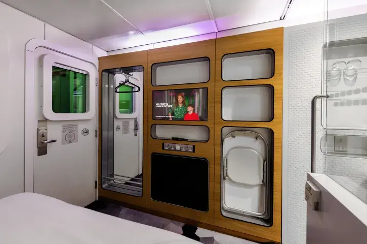 Smart storage solutions with a fold-out desk, TV, chair and bathroom in an Airport hotel