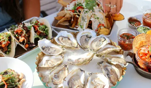 Restaurant table showing oysters, tacos and more food