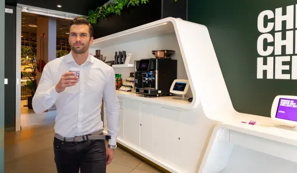 Man standing with coffee cup in front of food and drink display