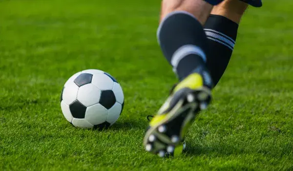A man kicks a football on a pitch
