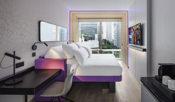 King size bed with desk and floor to ceiling window with city view