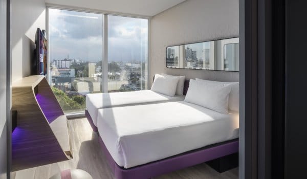 Room with twin beds, deck and floor to ceiling windows with city view 