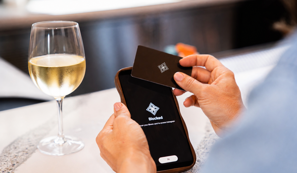A man taps a card to his mobile photo with a glass of white wine