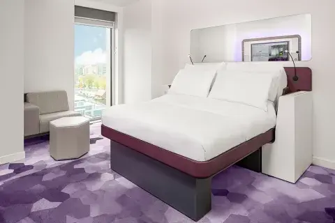 Hotel room in YOTEL Amsterdam with a large SmartBed and floor-to-ceiling windows