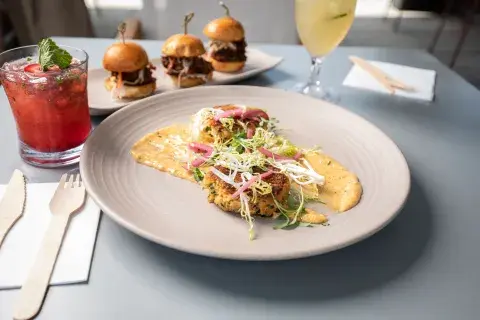 Three little burgers and a tasty main plate. The drink is red and fruity. 