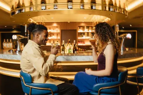 A couple chatting with cocktails at a round well-stocked bar