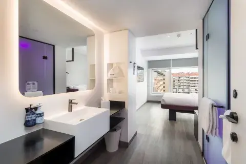 A large, well-lit and modern hotel room with purple accents and a big mirror