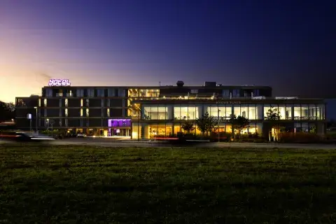 A hotel at night with a purple sky, surrounded by green fields