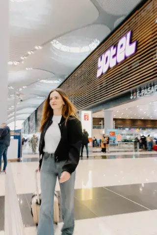 Woman walking through an airport with a large airport hotel in the background