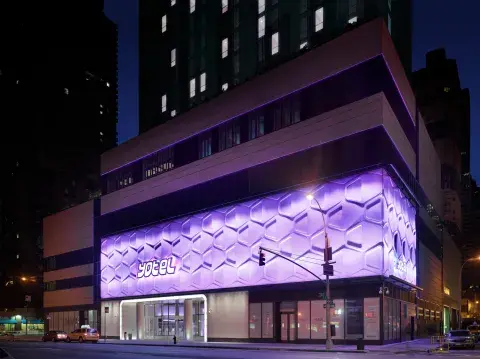 glowing purple YOTEL logo on the outside of NYC building