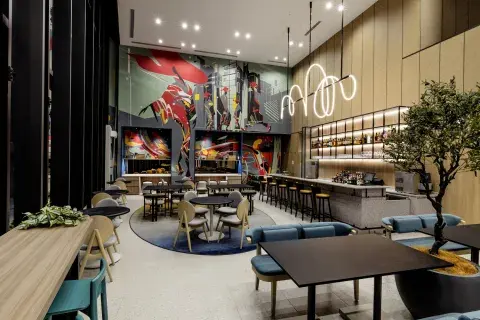 An arty open area of a bar and restaurant with wood panelled walls, sofa seating and bar stools