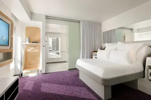 A spacious hotel room with a TV, bathroom and purple carpet