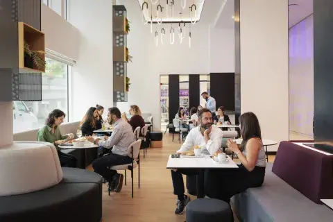 Smart-casually dressed guests enjoy socialising over drinks at a hotel bar and restaurant