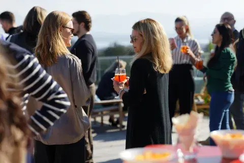 A group of people holding cocktails on a hotel rooftop