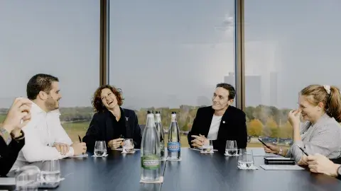 Four people sitting round a boardroom table, laughing 