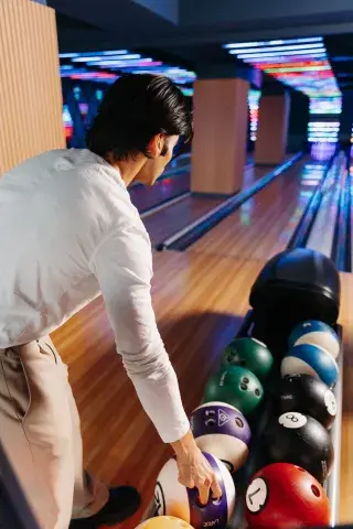 Man picking up bowling ball preparing to throw