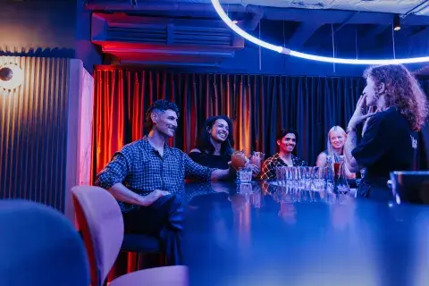 Group of people seated at bar listening to bartender speak